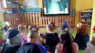 dzieci siedzą przed ekranem tablicy multimedialnej. Na ekranie napis Andrzejki