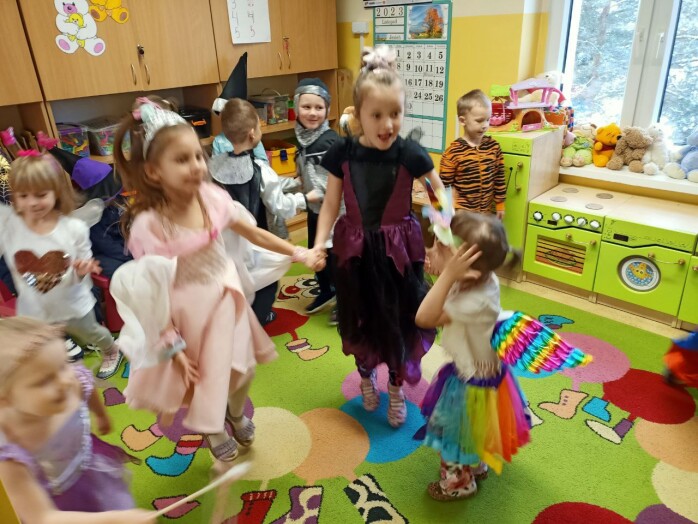 uśmiechnięte dzieci tańczą na sali przedszkolnej