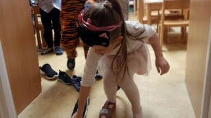 dziewczynka stawia bucik na progu wejścia do sali przedszkolnej