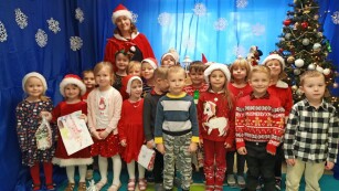 zdjęcie zbiorowe dzieci z nauczycielką na tle świątecznej dekoracji i choinki