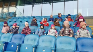 Grupa dzieci siedzi na trybunie w sektorze VIPowskim na stadionie Arena Lublin