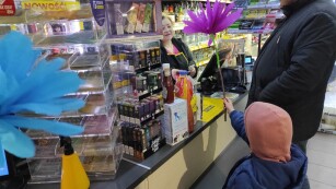 Dziewczynka wręcza bibułowy kwiat ekspedientce w sklepie