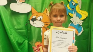 Dziewczynka prezentuje dyplom zdobyty w konkursie