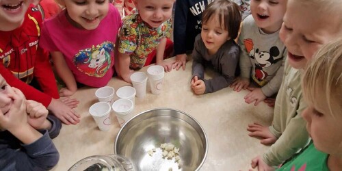 Dzieci stoją wokół stolika, przyglądają się jak działa urządzenie do robienia popcornu