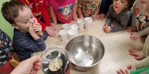 Dzieci stoją wokół stolika, przyglądają się jak działa urządzenie do robienia popcornu