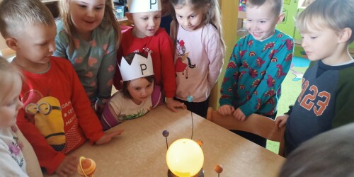 Dzieci oglądają ruchomy model Układu Słonecznego.