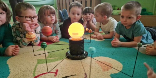 Dzieci oglądają mechaniczny model Układu Słonecznego