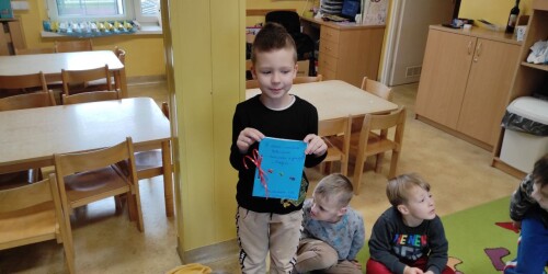 Chłopiec prezentuje prezent urodzinowy wykonany przez dzieci - książeczkę z rysunkami