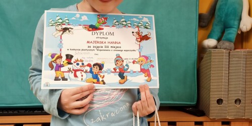 Dziewczynka prezentuje dyplom zdobyty za zajęcie III miejsca w konkursie