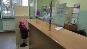 Dziewczynka wręcza bibułowy kwiat recepcjonistce w przychodni zdrowia