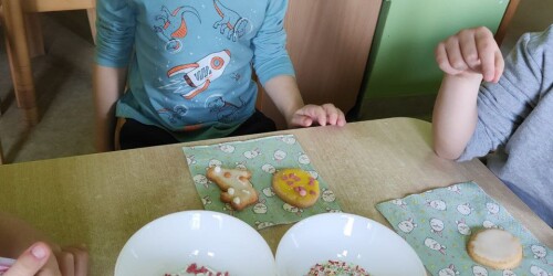 Dzieci ozdabiają ciasteczka lukrem i posypką