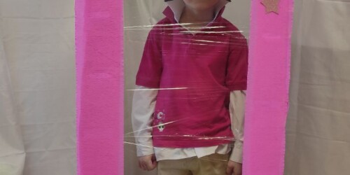 Chłopiec przebrany za Kena w fotobudce na kształt pudełka na lalkę Barbie