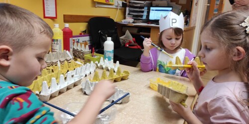 Dzieci malują farbami część wytłaczanki po jajkach