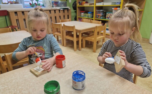 Dwie dziewczynki malują pędzelkiem styropianowe jaj ka kolorową farbą