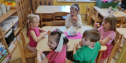 Dzieci przebrane za Barbie siedzą przy stolikach, jedzą słodki poczęstunek