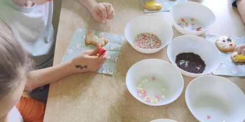 Dzieci ozdabiają ciasteczka lukrem i posypką